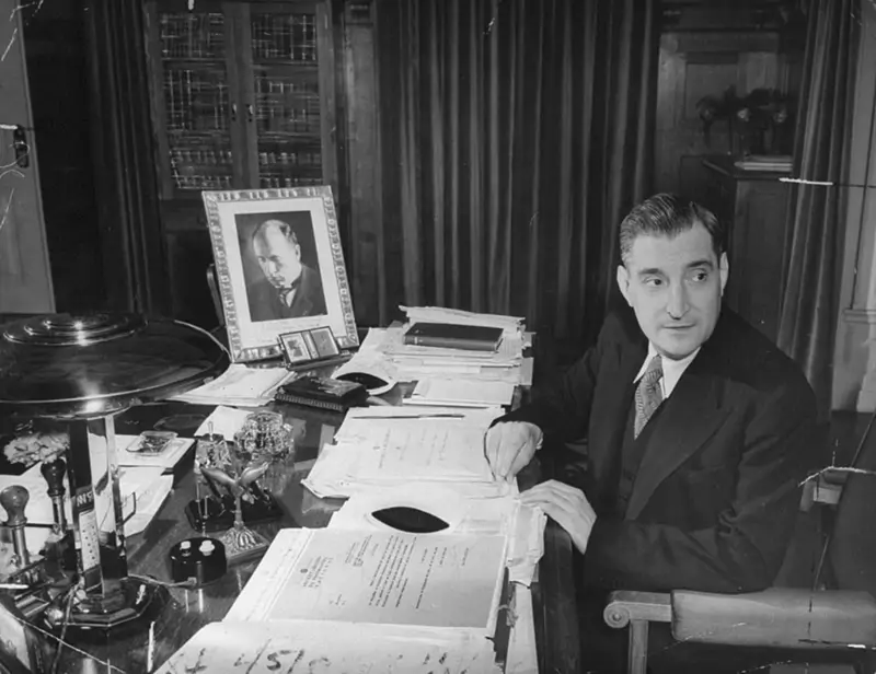 Salazar sentado à mesa de trabalho, com um retrato autografado de Il duce.